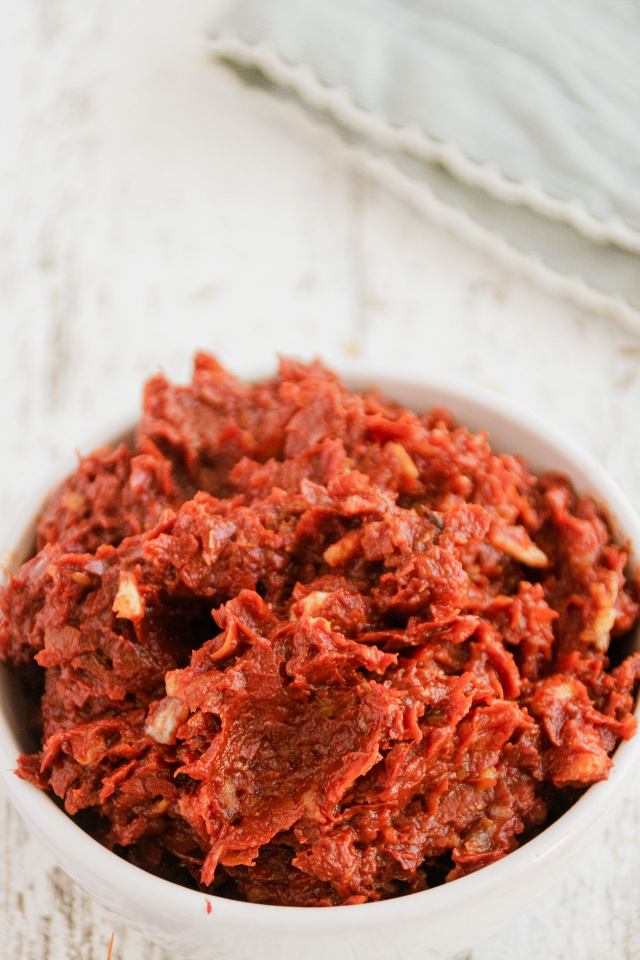 A small white bowl filled with thick, rich tomato paste