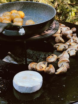 Enjoy an outdoor grilling scene with mushrooms, potatoes, and cheese on a griddle.