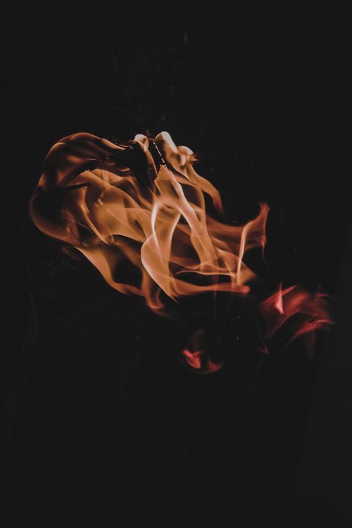 Free Close-up of vibrant flames dancing against a dark backdrop, creating a dramatic effect. Stock Photo