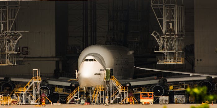 A Boeing airplane undergoing maintenance in a massive aircraft hangar.