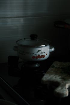 A vintage pot with cherry design on a gas stove in dim lighting. Cozy kitchen atmosphere.