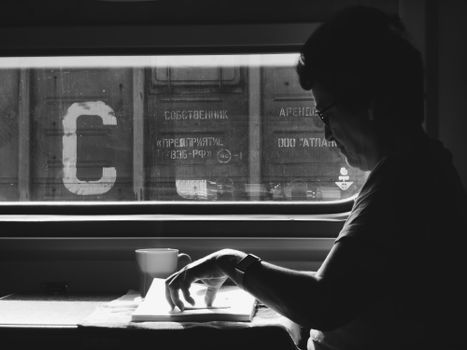 A woman reading a book on a train in black and white. Captivating light and shadow contrast.