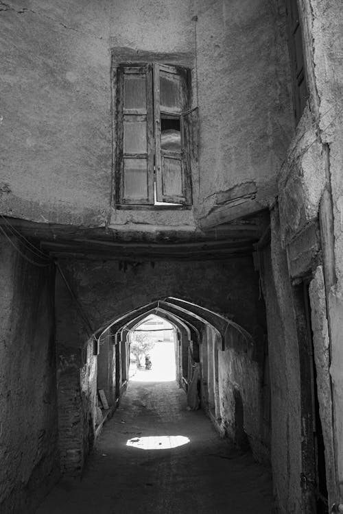 Grayscale Photo of a Narrow Arched Alley