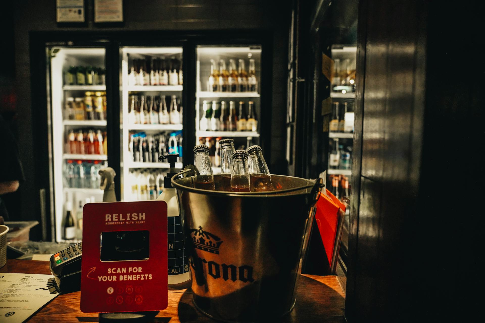 Cozy bar setup with beer bottles in a bucket and a payment terminal on the counter.