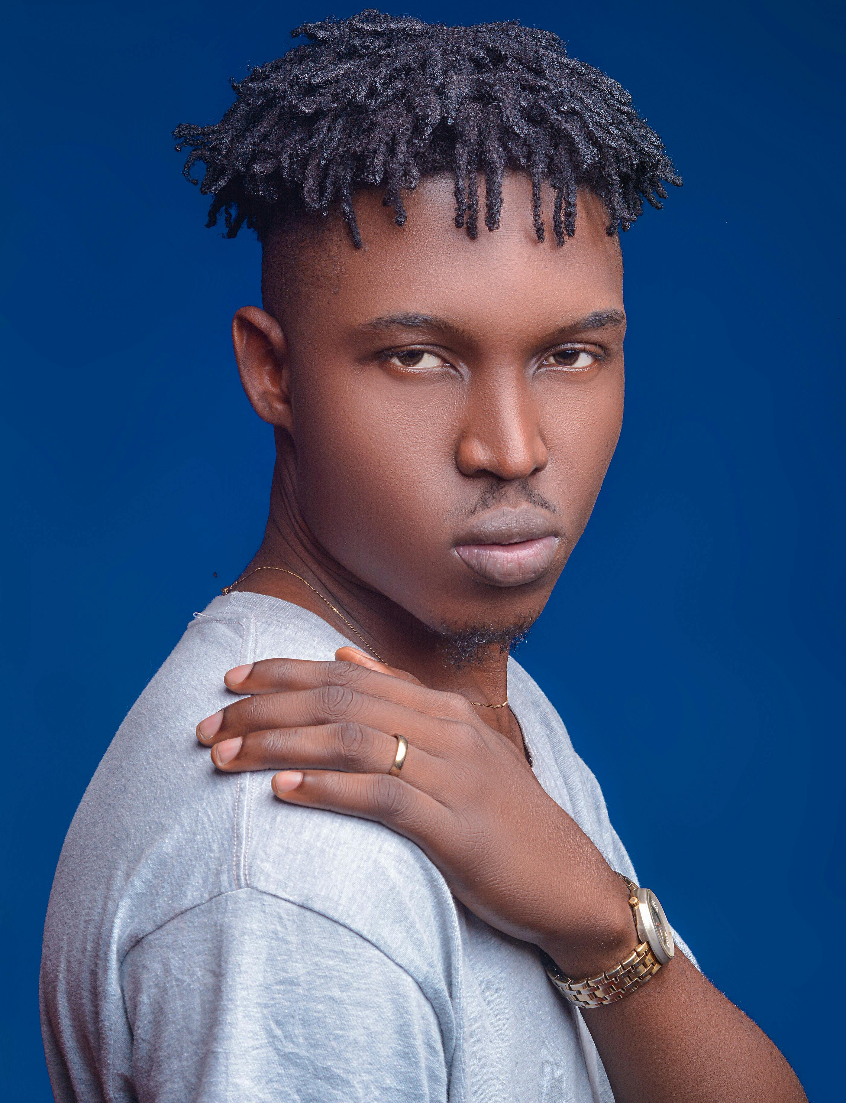 一位时尚的黑人男子特写肖像，在蓝色背景下，他梳着辫子，摆出凶猛的姿势