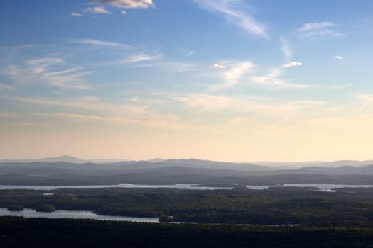 A tranquil view of mountains and river under a serene sky during dawn.