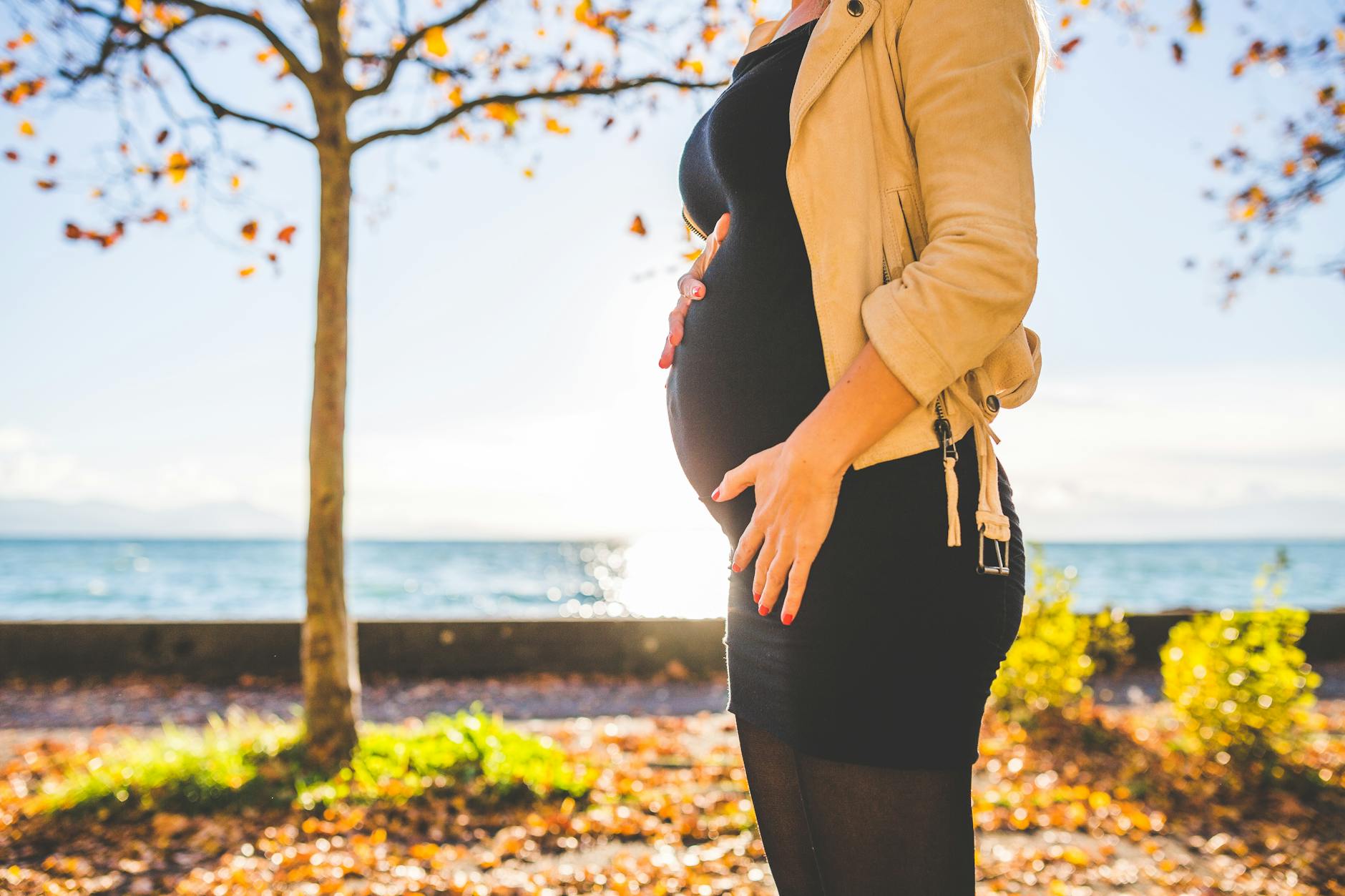 Pregnant Woman standing at the park while holding her belly