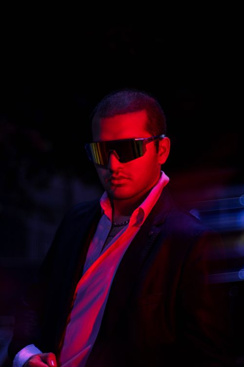 Free A man in a black suit and futuristic sunglasses under vibrant lighting, exuding coolness. Stock Photo