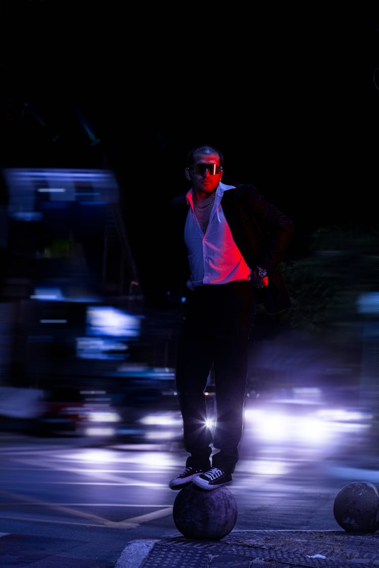 Man In Black Suit Wearing Sunglasses Standing On A Round Cobble Stone