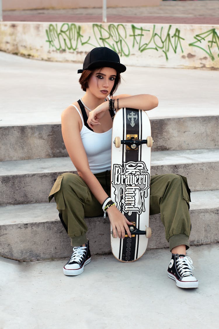 Woman Sitting On Steps While Holding Skateboard