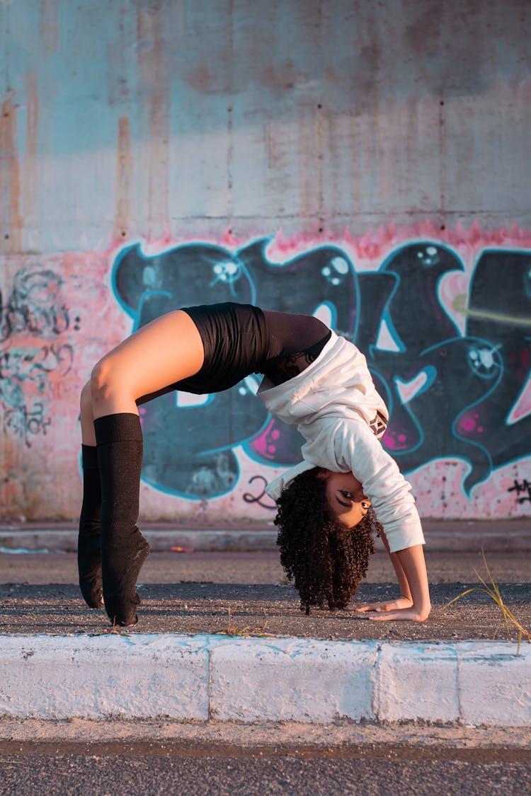 Young Woman In Active Wear Bending On Street