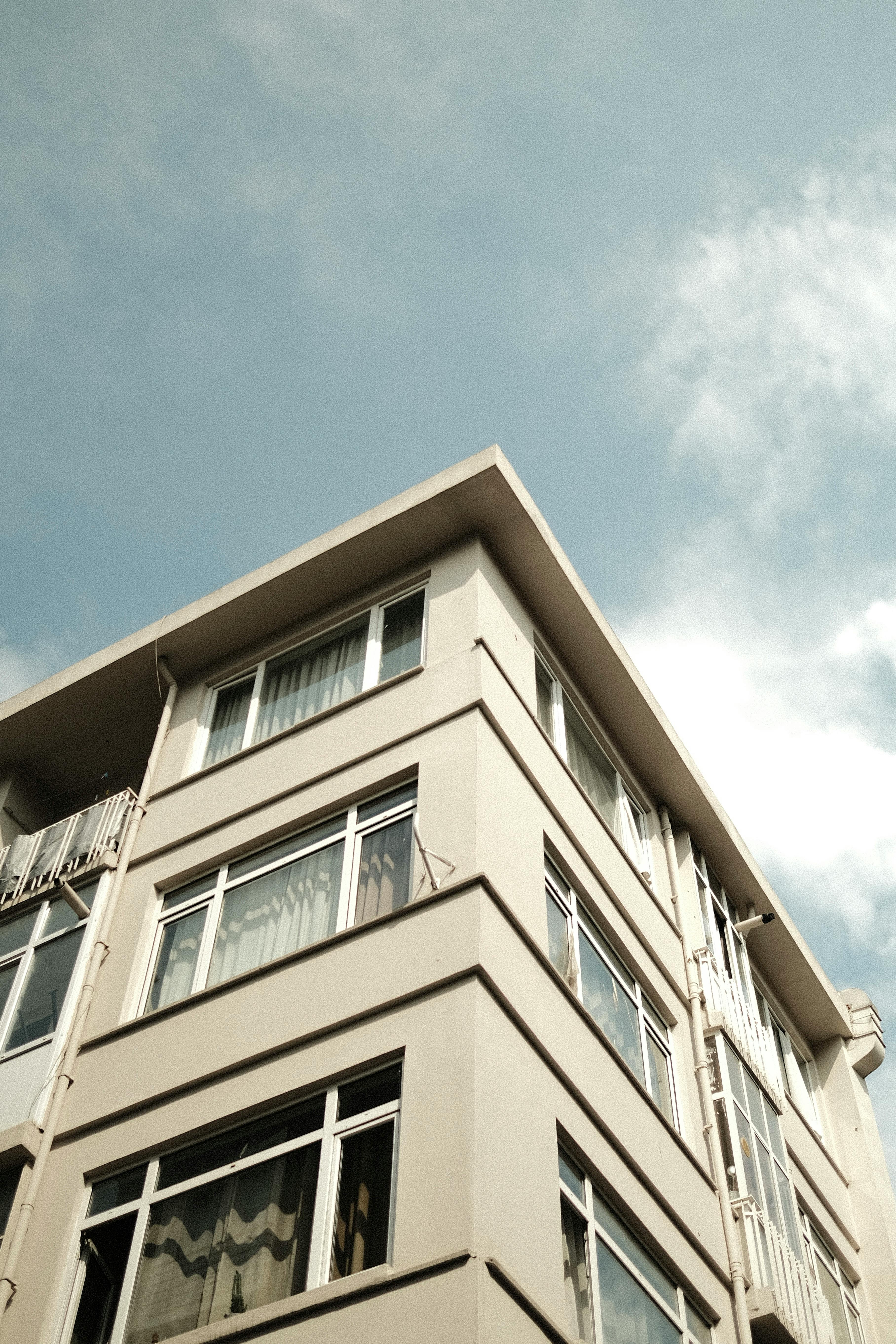 Free Low angle view of a contemporary apartment building with clear blue sky and clouds. Stock Photo