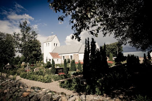 郁郁葱葱的花园中有一座美丽的教堂，树木和岩石在晴朗的天空下