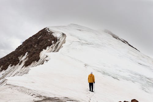 Free Man Climbing Snow Covered Hill Stock Photo