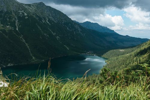 Free Majestic view of a serene lake surrounded by Tatra Mountains under a cloudy sky in Poland. Stock Photo