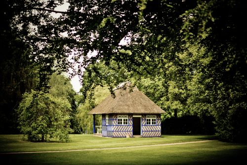 Free Quaint thatched cottage amid lush greenery, evoking pastoral charm and tranquility. Stock Photo