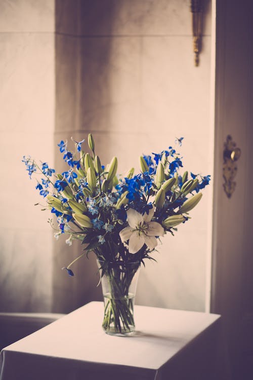 Blauwe En Witte Bloemen In Helderglazen Vaas Op Witte Tafel