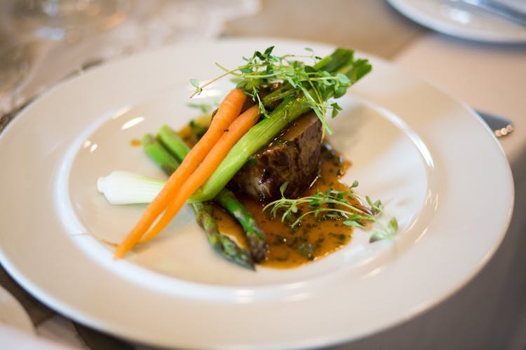 Cooked Meat With Vegetable Garnish On White Plate