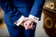 特写镜头中，一位身着蓝色西装的成年人双手交叉，尽显优雅与商务风范