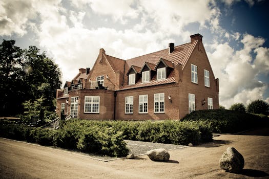 Elegant brick mansion with landscaped garden under a bright sunny sky.