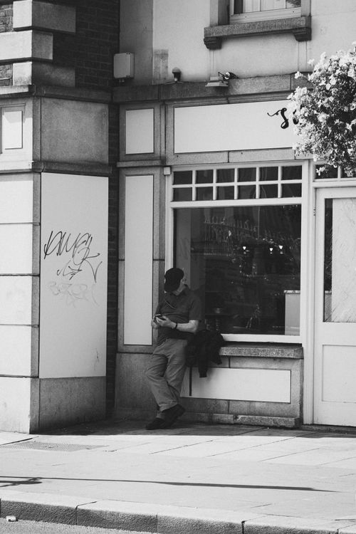 Free Black and white urban scene in Dublin showing a person leaning against a building with graffiti. Stock Photo