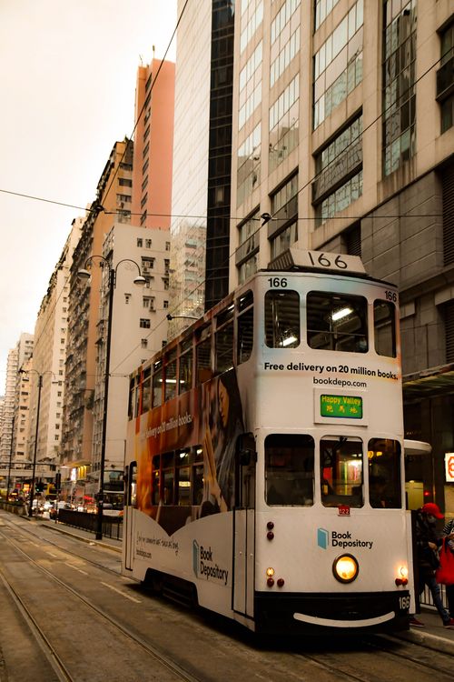 Free A classic double-decker tram moves through bustling downtown streets in a vibrant city atmosphere. Stock Photo