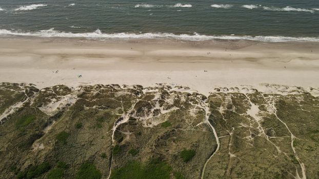 Stunning aerial view of Henne Beach, Denmark with dunes and waves under summer skies.