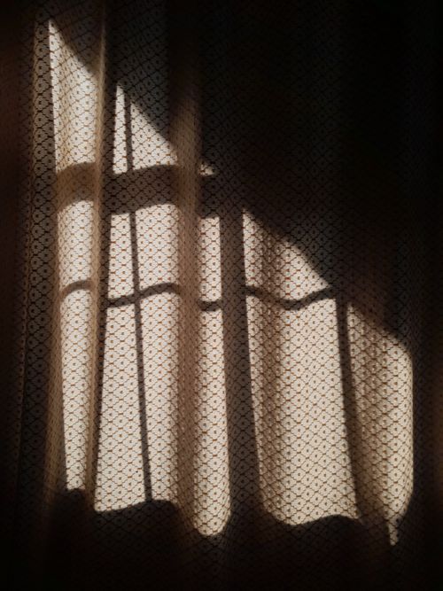 Free Soft shadows and light filtering through patterned curtains create a serene indoor scene. Stock Photo