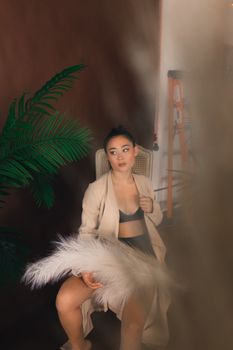 Stylish Asian woman posing indoors, showcasing modern fashion with a confident look.