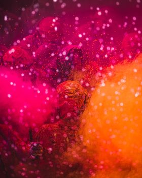 Colorful Holi festival scene with people covered in vibrant pink and orange powder.