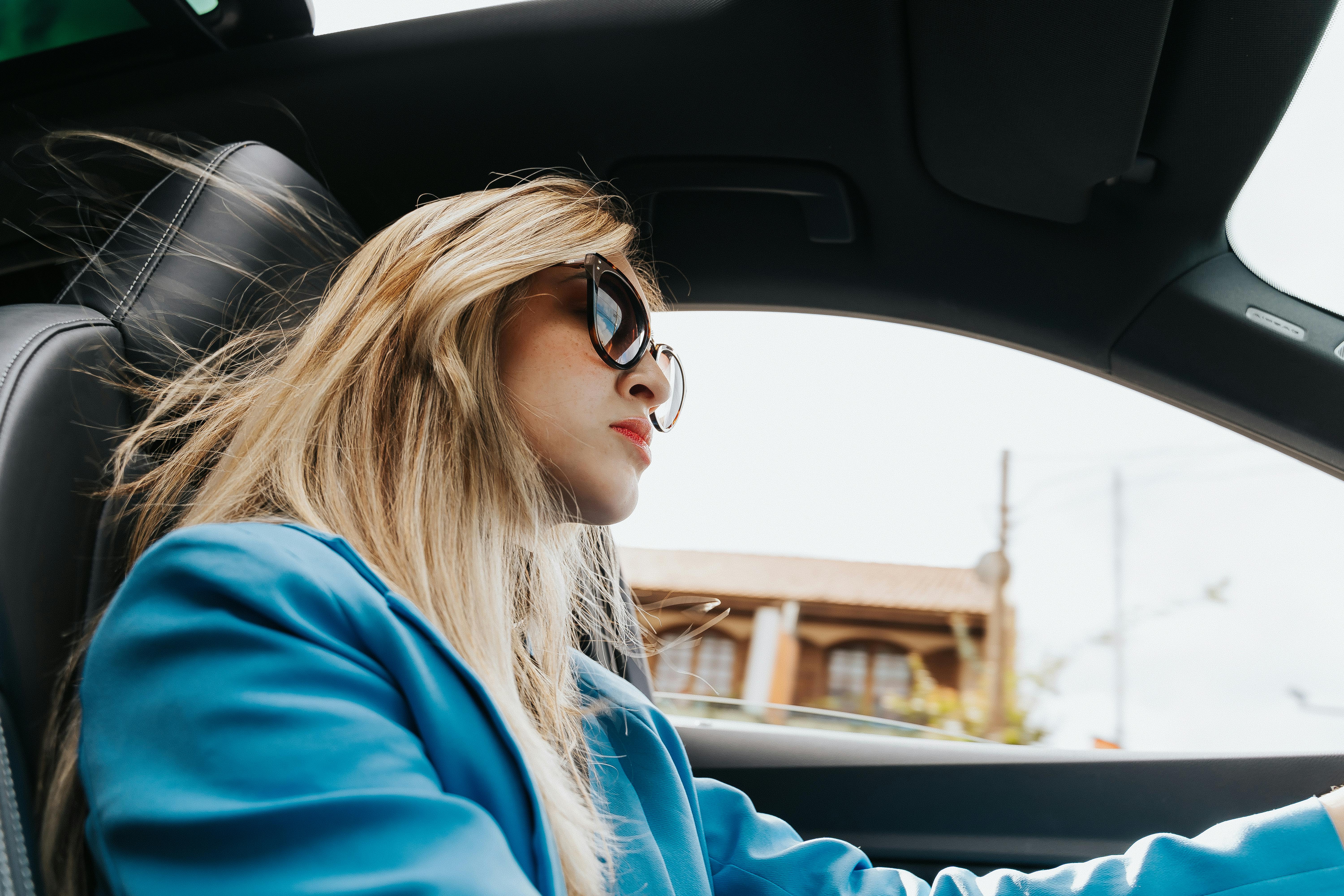 a woman in blue blazer driving a car