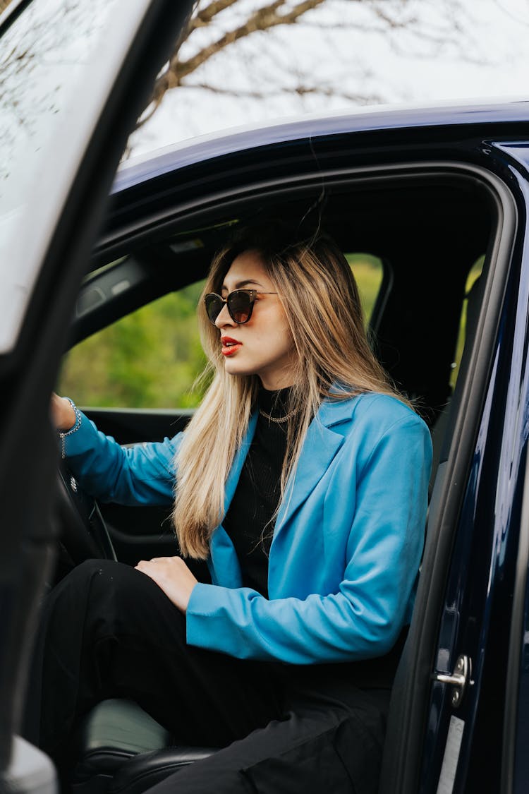 Elegant Woman In Sunglasses Sitting Behind The Wheel In A New Car 