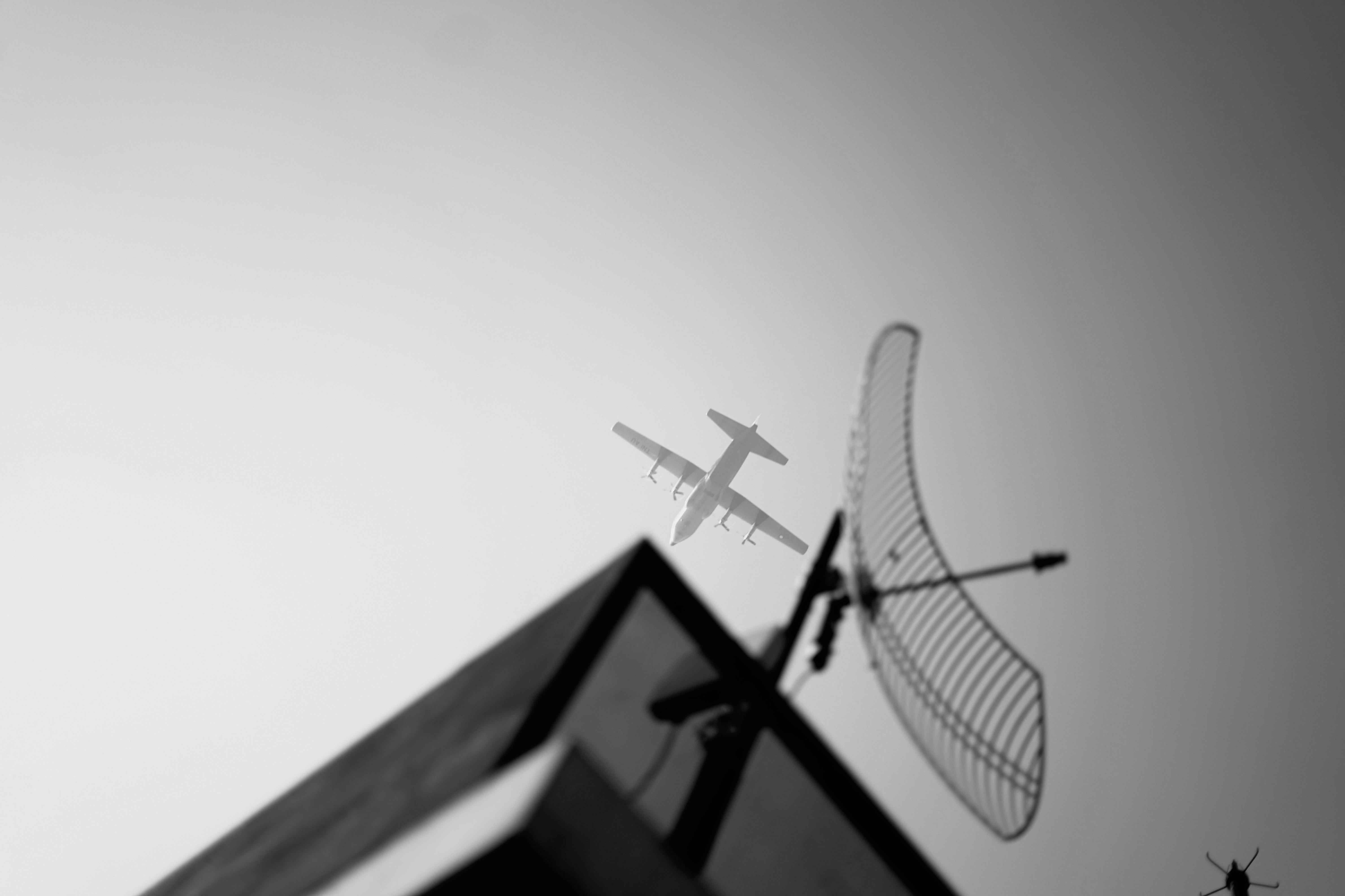 Free A black and white photo of an airplane flying over an antenna in Jawa Barat, Indonesia. Stock Photo