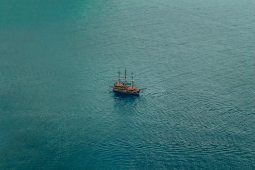 A lone ship sailing on the vast open sea captured from above. Serene and expansive view.