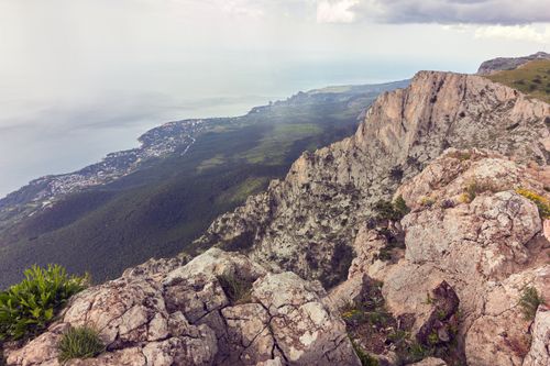 Free Majestic cliffs and lush greenery along a breathtaking rocky coastline against the sea. Stock Photo