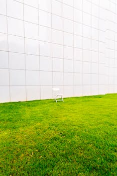 White chair on green grass with tiled wall backdrop in Atlanta, Georgia.