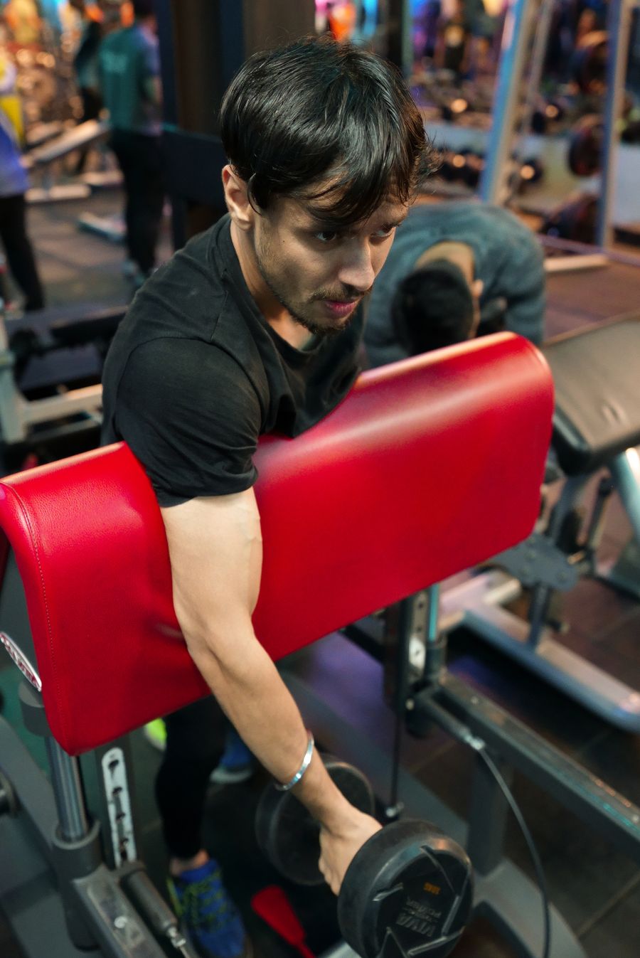 Indian man performing a dumbbell workout in a gym