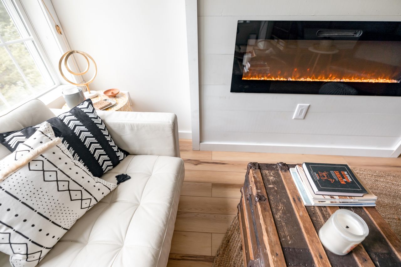 White sofa beside a fireplace with a vintage wooden trunk used as a coffee table