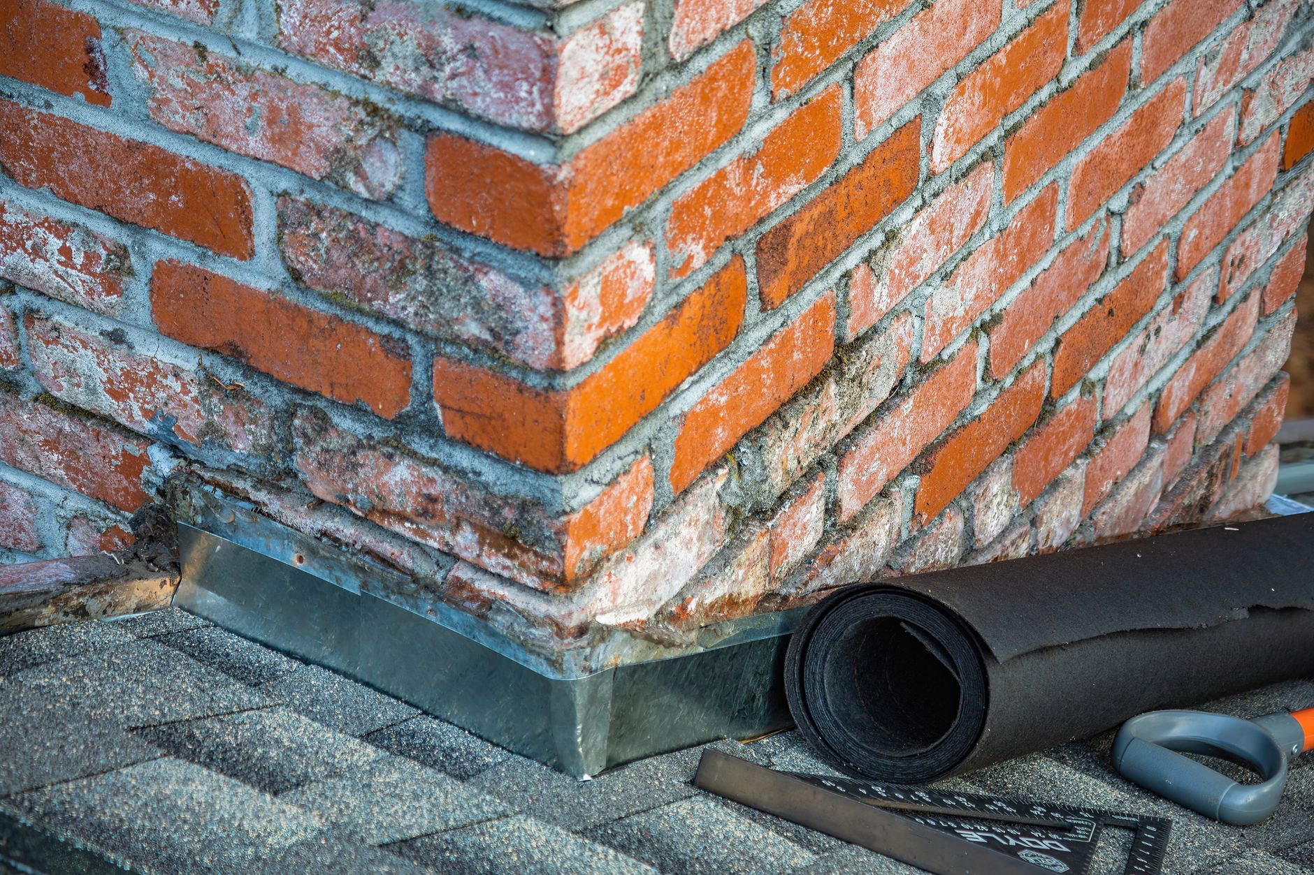 Brick chimney repair — close-up of masonry work and construction tools on a residential chimney