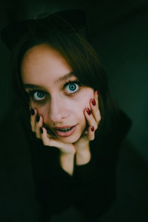 Free Intriguing close-up of a woman with striking blue eyes, braces, and red nails. Stock Photo