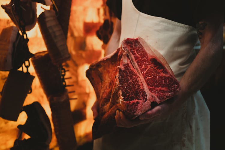 A Butcher Holding A Slab Of Steak