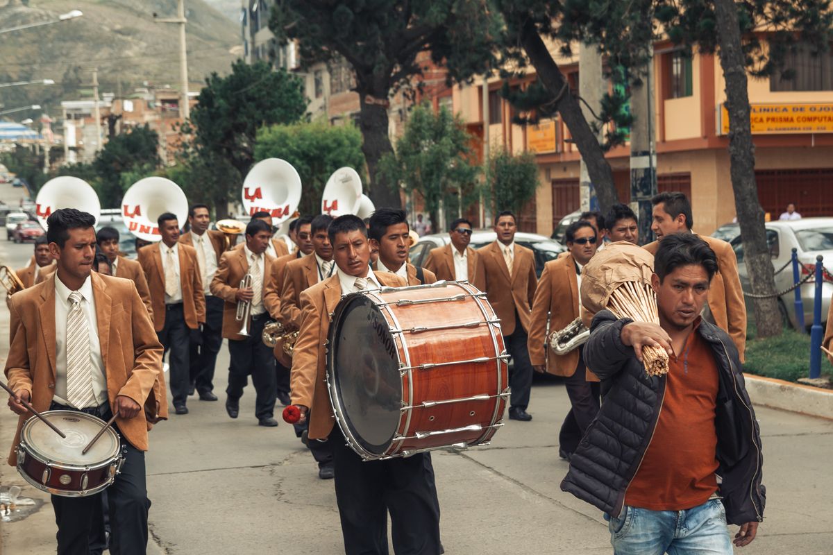 Banda de música con chaquetas de uniforme marrón desfilando por una calle de la ciudad