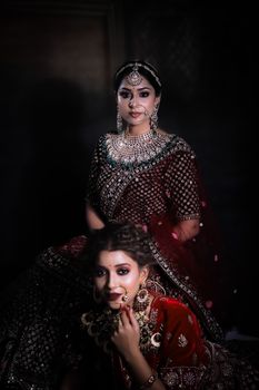 Portrait of two women in traditional Indian attire with intricate jewelry, exuding elegance.