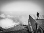 A man leaning on metal railings on a viewing deck at Sant'Elia di Palmi, Calabria, Italy, overlooking a misty mountain view.