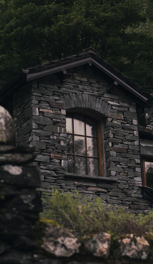 Free Beautiful stone house facade with window amidst lush greenery, showcasing rustic architecture. Stock Photo