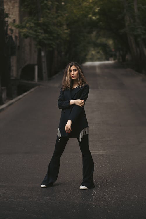 Free A Woman in Black Clothing Standing in the Middle of the Street Stock Photo