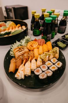 Vibrant assorted sushi platter showcased on a table with soy sauce bottles in the background.