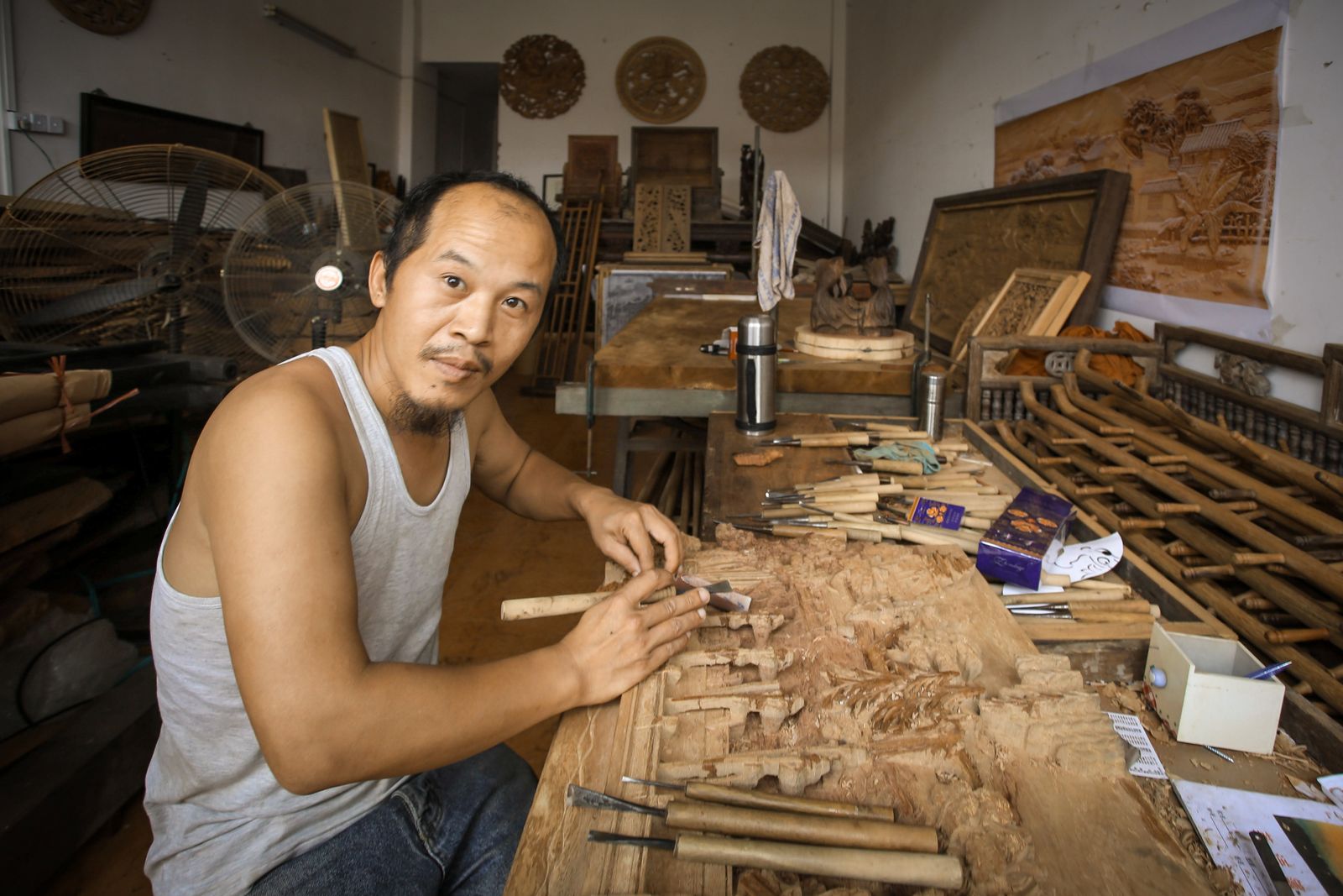 Artisan holding a chisel while shaping wood, evoking the traditional hand-tool craft passed through generations