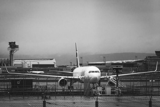 Monochrome image of an airplane parked at an airport gate.