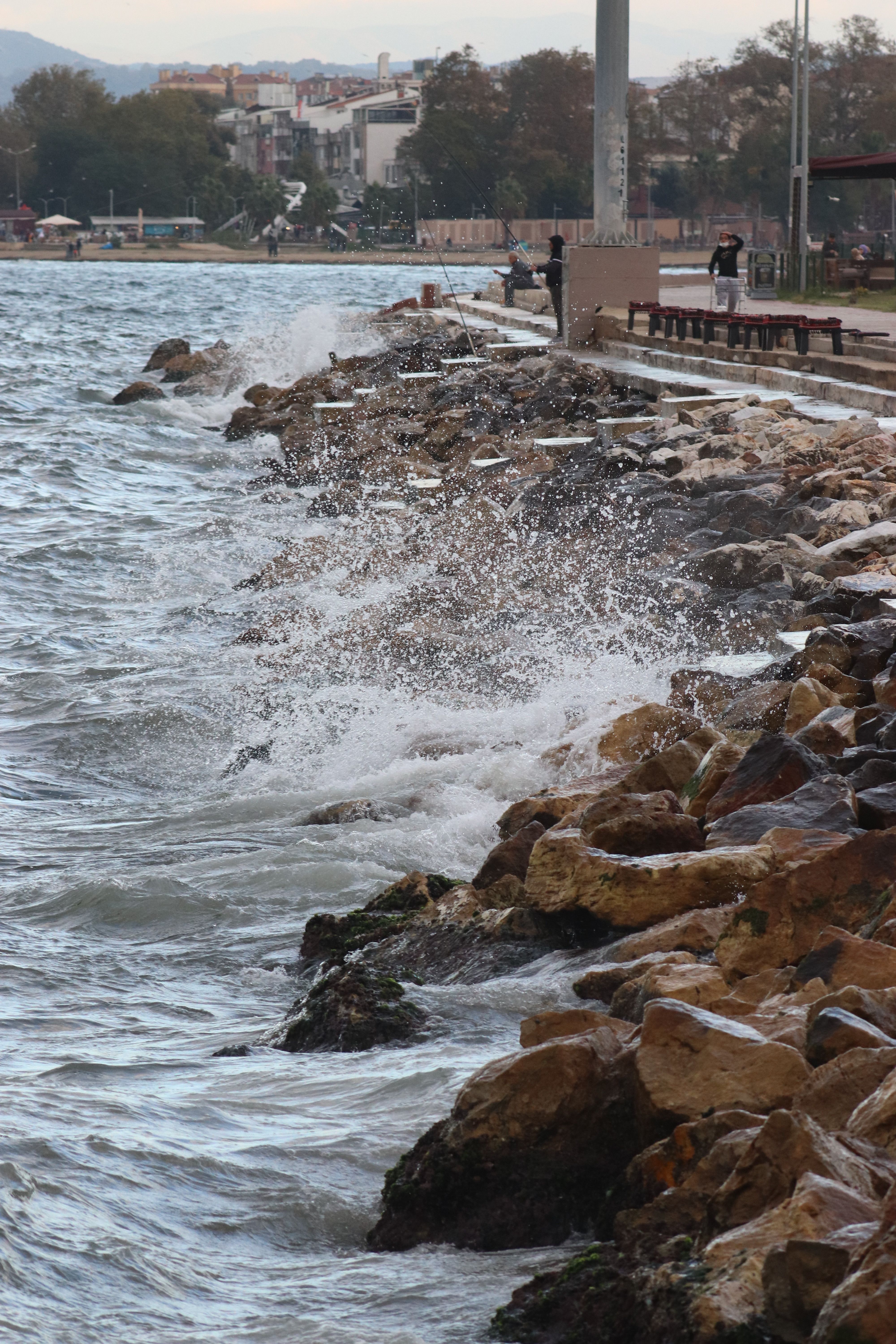 Dynamic waves crash against a rock breakwater in a scenic coastal setting, capturing the power of nature.